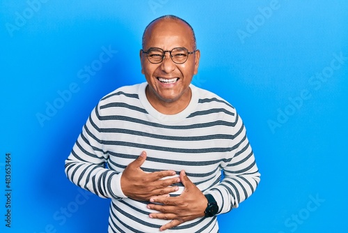 Middle age latin man wearing casual clothes and glasses smiling and laughing hard out loud because funny crazy joke with hands on body.