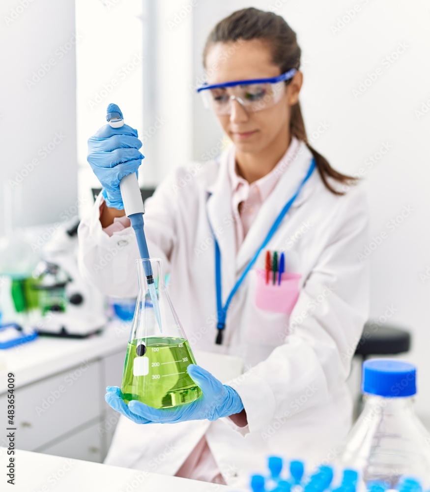 Young hispanic woman wearing scientist uniform using pipette and test tube working at laboratory Young hispanic woman wearing scientist uniform using pipette and test tube working at laboratory