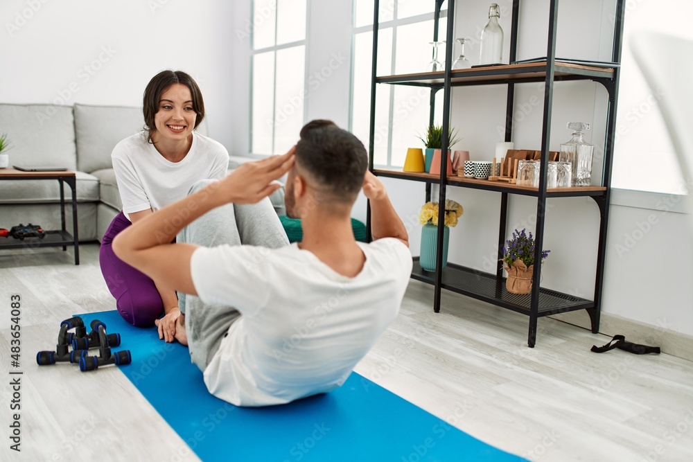 Young hispanic couple doing abs exercise at home Young hispanic couple doing abs exercise at home