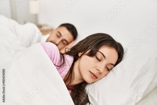 Young hispanic couple sleeping on bed at home.