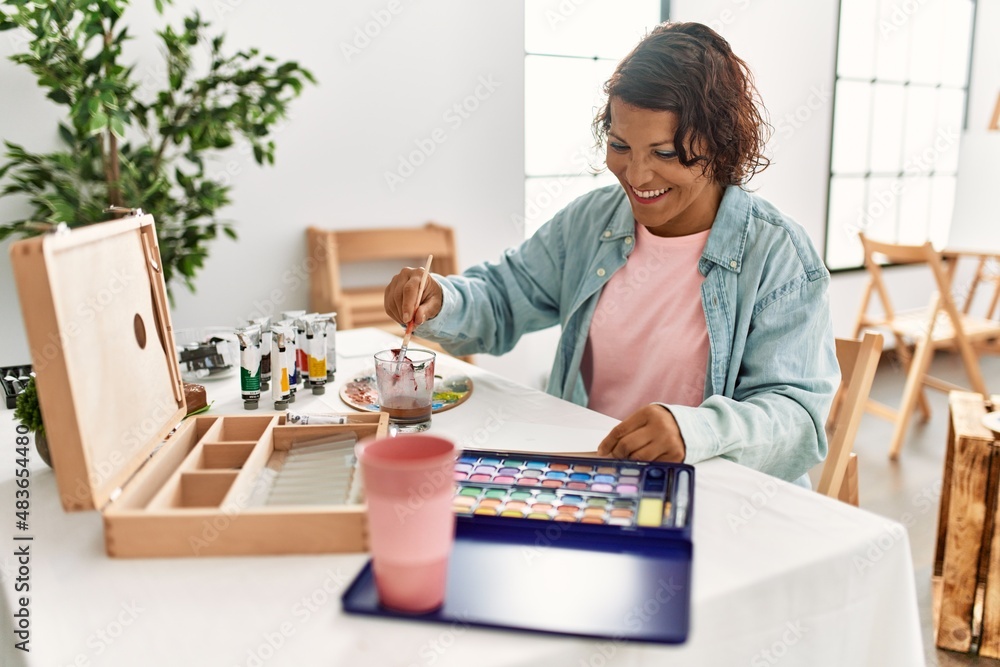 Middle age hispanic artist woman smiling happy drawing at art studio.