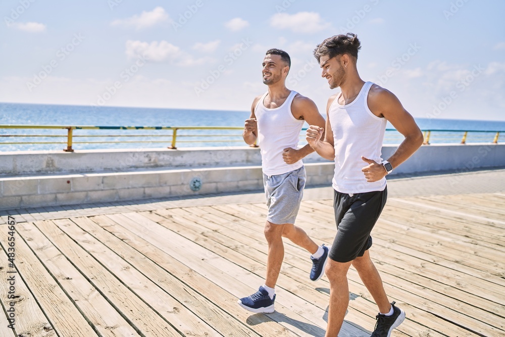 Two hispanic men sporty couple smiling confident running at seaside Two hispanic men sporty couple smiling confident running at seaside
