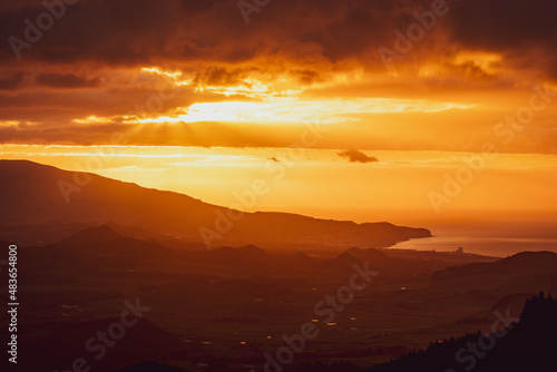 Sunrise over landscape with mountains, orange light, sun rising. © Ayla Harbich