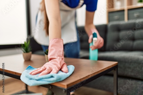 Fotografia Woman cleaning table using rag and diffuser at home.