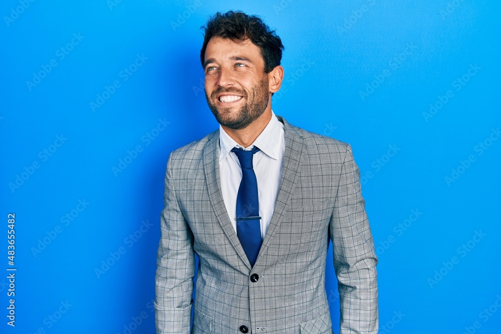Handsome man with beard wearing business suit and tie looking away to side with smile on face, natural expression. laughing confident. Handsome man with beard wearing business suit and tie looking away to side with smile on face, natural expression. laughing confident.