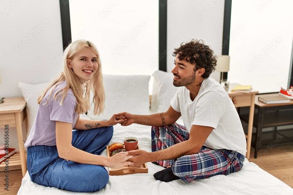 Young beautiful couple smiling happy having breakfast on the bed at home. Young beautiful couple smiling happy having breakfast on the bed at home.