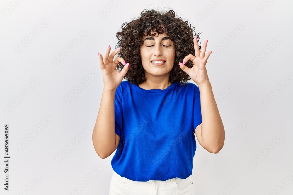 Young middle eastern woman standing over isolated background relax and smiling with eyes closed doing meditation gesture with fingers. yoga concept. Young middle eastern woman standing over isolated background relax and smiling with eyes closed doing meditation gesture with fingers. yoga concept.