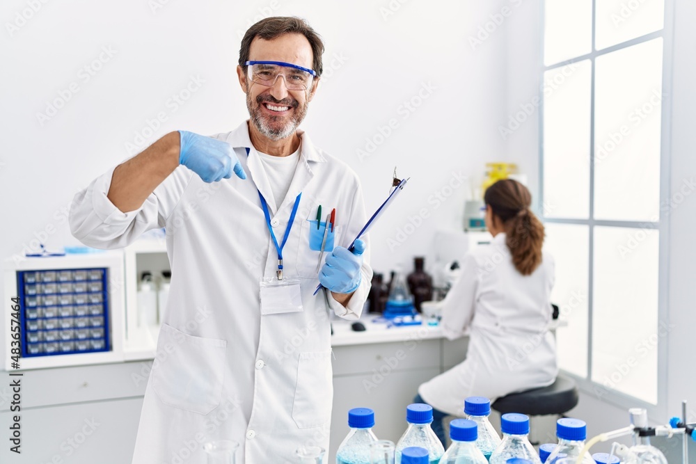 Middle age man working at scientist laboratory pointing finger to one self smiling happy and proud Middle age man working at scientist laboratory pointing finger to one self smiling happy and proud