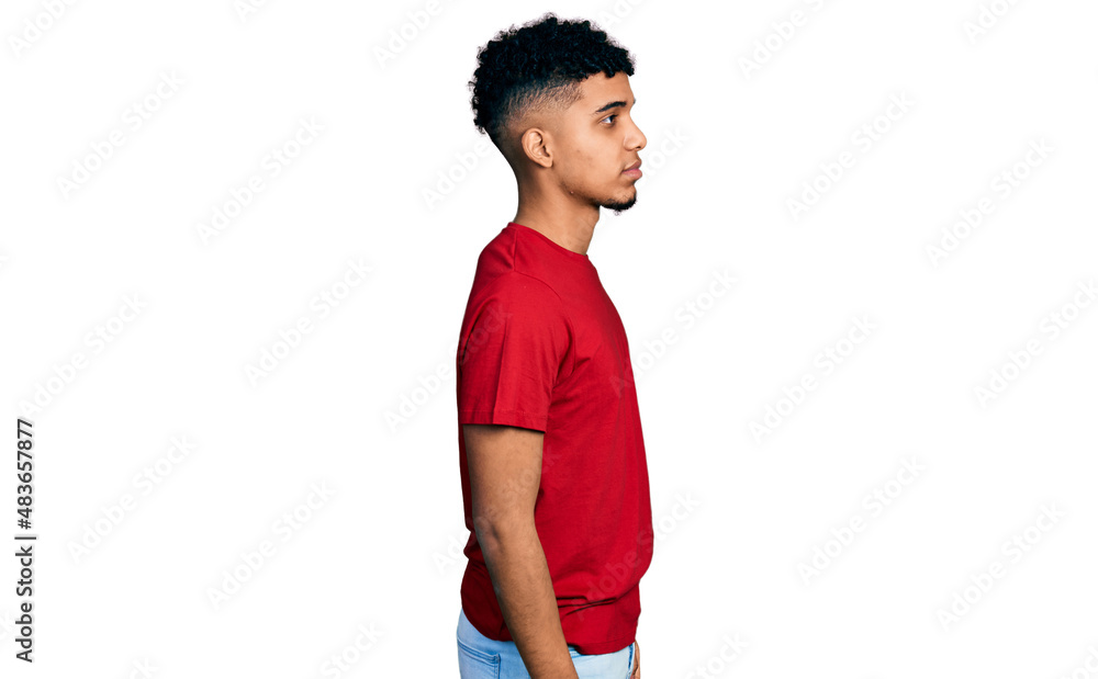 Young african american man wearing casual red t shirt looking to side, relax profile pose with natural face with confident smile. Young african american man wearing casual red t shirt looking to side, relax profile pose with natural face with confident smile.