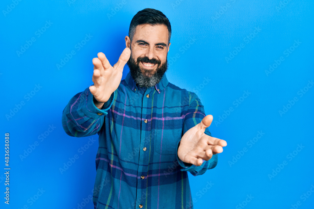 Young hispanic man wearing casual clothes looking at the camera smiling with open arms for hug. cheerful expression embracing happiness. Young hispanic man wearing casual clothes looking at the camera smiling with open arms for hug. cheerful expression embracing happiness.