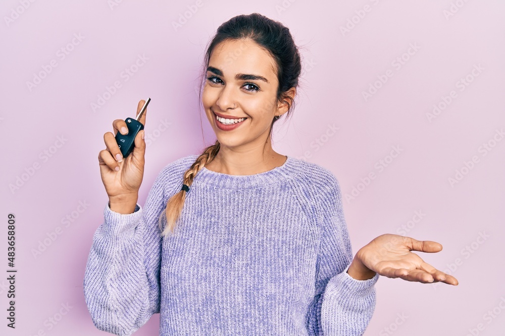 Young hispanic girl holding key of new car celebrating achievement with happy smile and winner expression with raised hand Young hispanic girl holding key of new car celebrating achievement with happy smile and winner expression with raised hand
