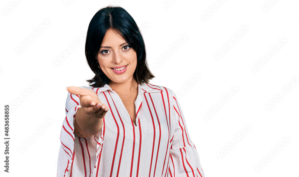 Young hispanic girl wearing casual clothes smiling cheerful offering palm hand giving assistance and acceptance.