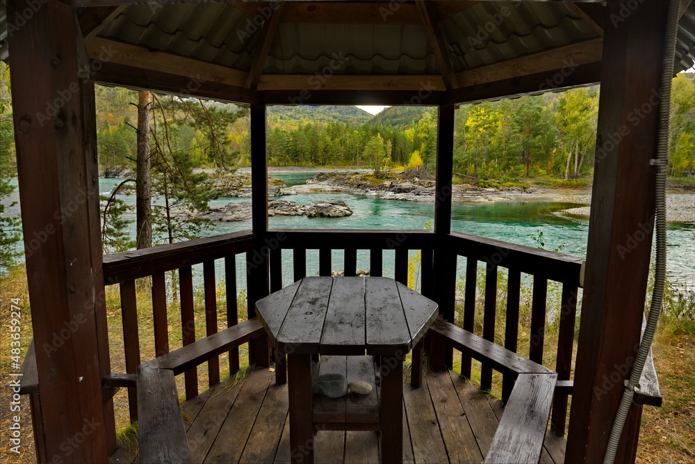 Russia. The South of Western Siberia, the Altai Mountains. Panoramic view of the Katun River through a wooden gazebo in a tourist campsite near the village of Manzherok.