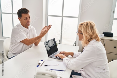 Middle age man and woman doctor and patient having medical consultation at clinic