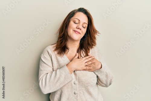 Young caucasian woman wearing casual clothes smiling with hands on chest with closed eyes and grateful gesture on face. health concept.