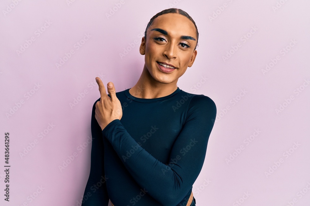 Obraz premium Hispanic man wearing make up and long hair wearing casual clothes smiling cheerful pointing with hand and finger up to the side