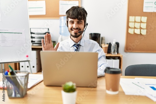 Young hispanic call center agent man having video call working at the office.