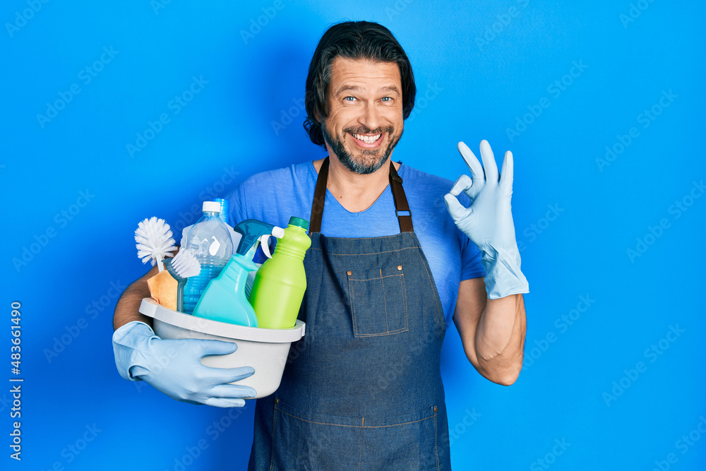 Middle age caucasian man holding cleaning products doing ok sign with fingers, smiling friendly gesturing excellent symbol Middle age caucasian man holding cleaning products doing ok sign with fingers, smiling friendly gesturing excellent symbol