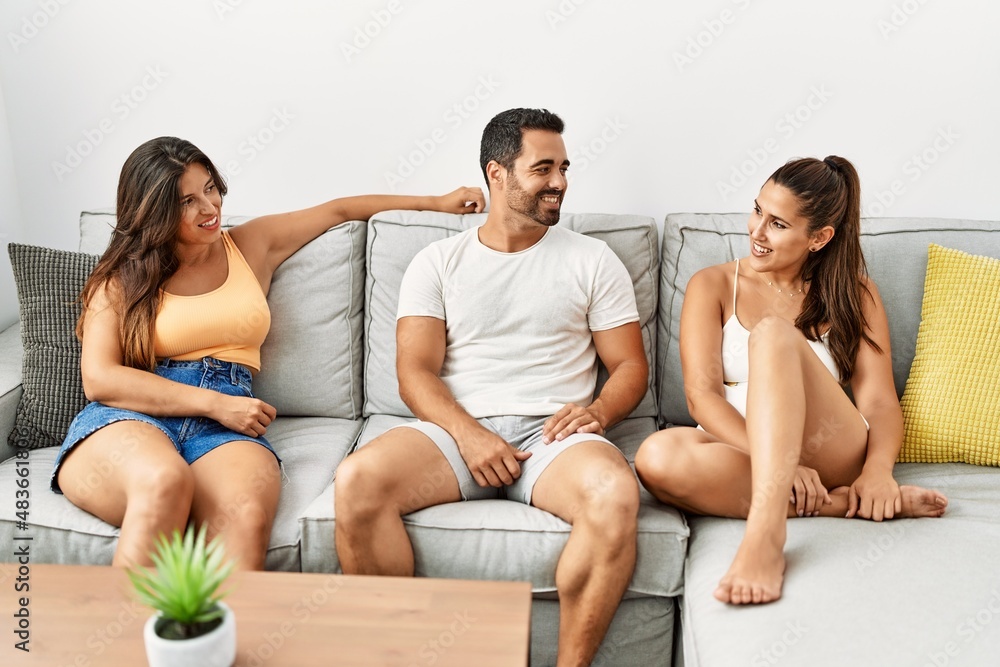 Three hispanic friends smiling happy sitting on the sofa at home.