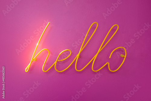 Wall-mounted metal "hello" sign on a pink wall (ID: 483662060)