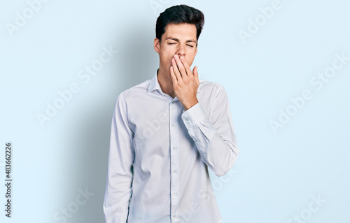 Young hispanic business man wearing business clothes bored yawning tired covering mouth with hand. restless and sleepiness.