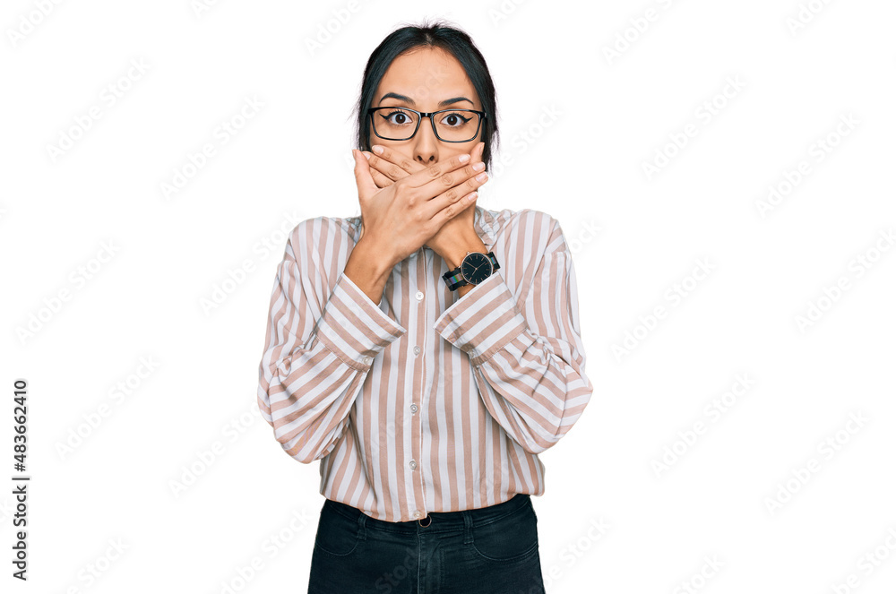 Young hispanic girl wearing casual clothes and glasses shocked covering mouth with hands for mistake. secret concept. Young hispanic girl wearing casual clothes and glasses shocked covering mouth with hands for mistake. secret concept.