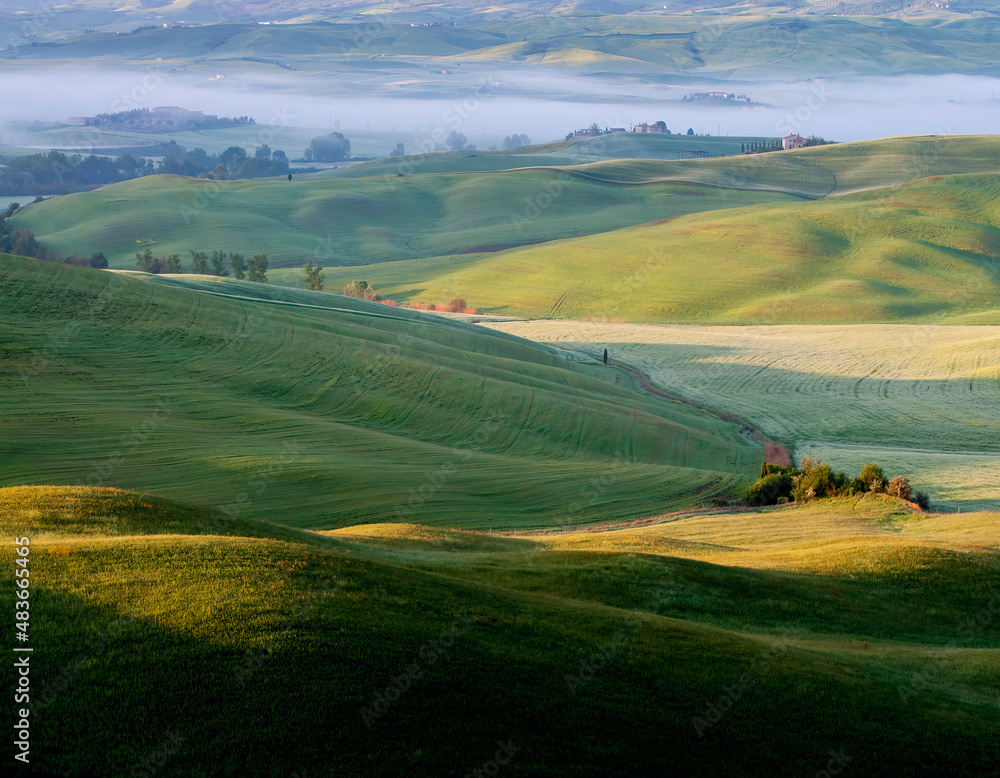 Spring Tuscany. View of the sunlit hills. There is fog in the valley.