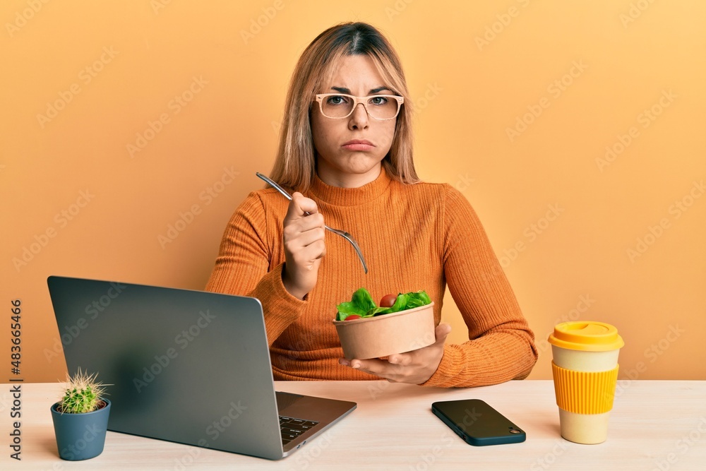Young caucasian woman working at the office eating healthy salad depressed and worry for distress, crying angry and afraid. sad expression. Young caucasian woman working at the office eating healthy salad depressed and worry for distress, crying angry and afraid. sad expression.