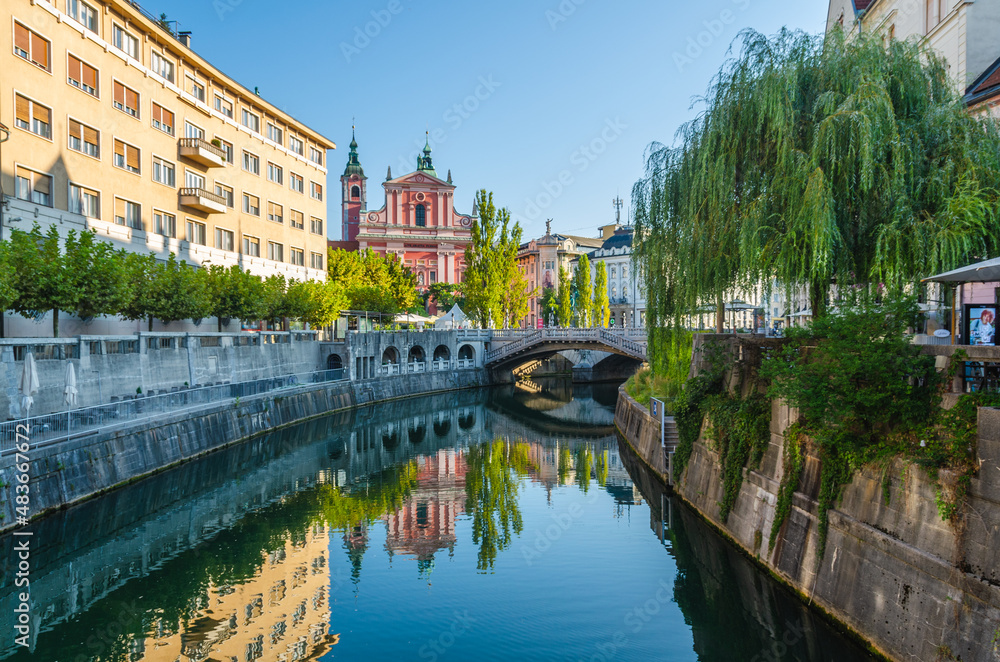 Franciscan Church of the Annunciation and Triple Bridge reflected in Ljublanica river, Ljubljana, Slovenia