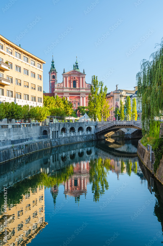 Franciscan Church of the Annunciation and Triple Bridge reflected in Ljublanica river, Ljubljana, Slovenia