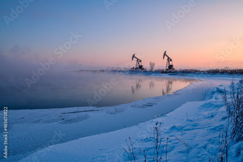 The oil pumping units in lakeside in winter in Daqing oil fields, China.