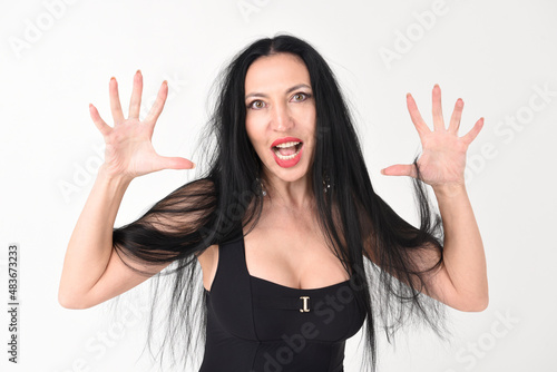 Portrait of a beautiful brunette woman in an explosive fighting pose ready to fight and scratch in hysterics with an evil face