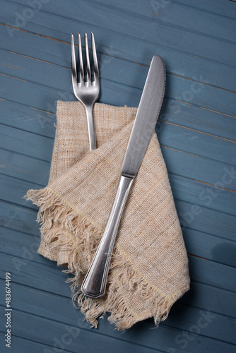 steel fork and knife with napkin on blue table #483674499