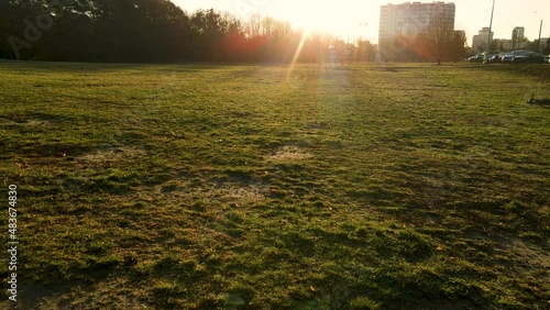 Low angle flying over the flat meadow pitching up towards setting sun in urban Gdansk Przymorze photo