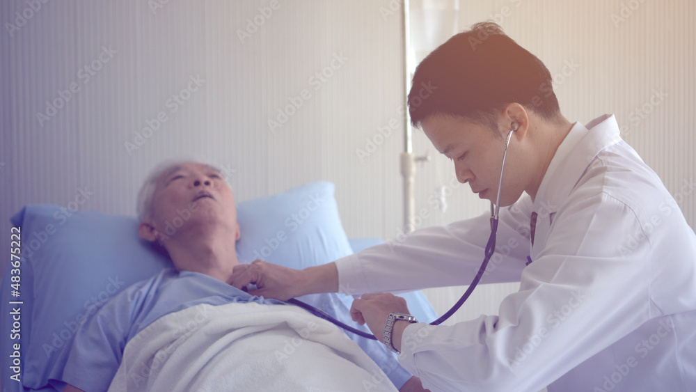 Asian doctor checking heart and pulse on senior in hospital bed with stethoscope Asian doctor checking heart and pulse on senior in hospital bed with stethoscope