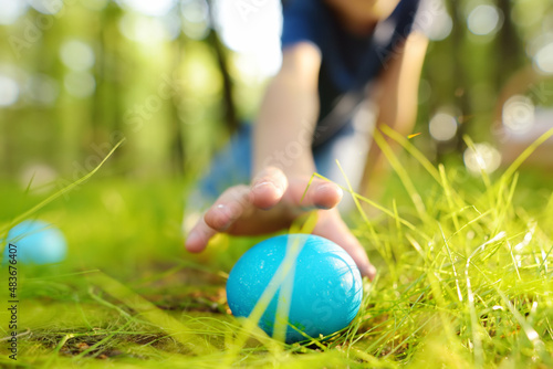 Fotografiet Little boy hunting for egg in spring garden on Easter day