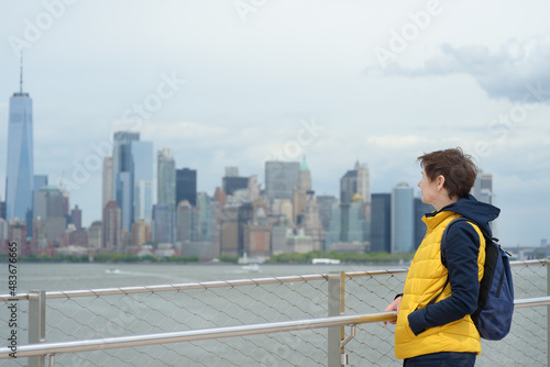 Woman tourist is admiring of famous panorama of Manhattan from island of Liberty, New York, USA.