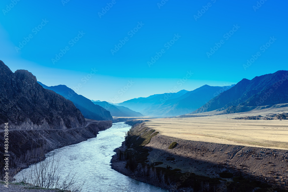Blue mountain hills with tonal perspective at early spring. Abstract panoramic landscape in Altai Republic, Altai mountains, Russia. Blue clear sky, mountains and river, nature environment