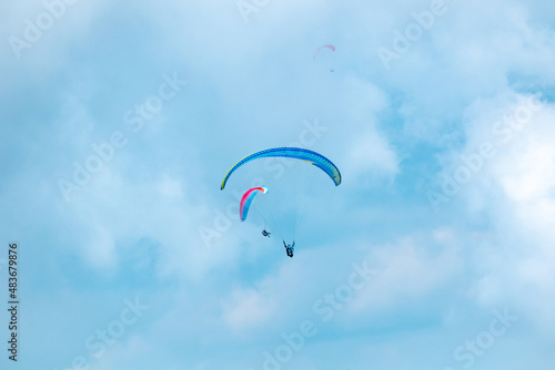 Belmira, Antioquia, Colombia - November 20 2021: Blue and Pink Paragliders, Flying on a Blue Background full of Clouds photo