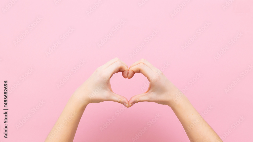 Fototapeta premium Banner young woman holding hands in shape of heart on pink background.