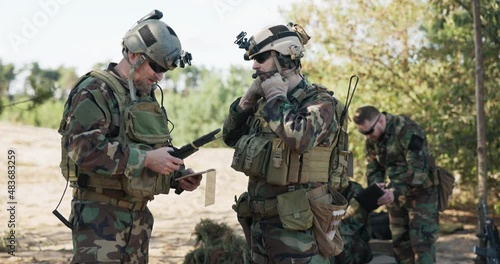 Soldiers belonging to powerful army are preparing strategy for battle surprise enemy enter data into system talk prepare equipment dressed in uniforms camouflage helmets training ground