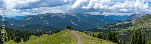 Storm Mountains - A panoramic view of Anthracite Range of West Elk Mountains, surrounded by dense evergreen forest, as seen from Scarp Ridge Trail on a stormy Summer day. Crested Butte, Colorado, USA.