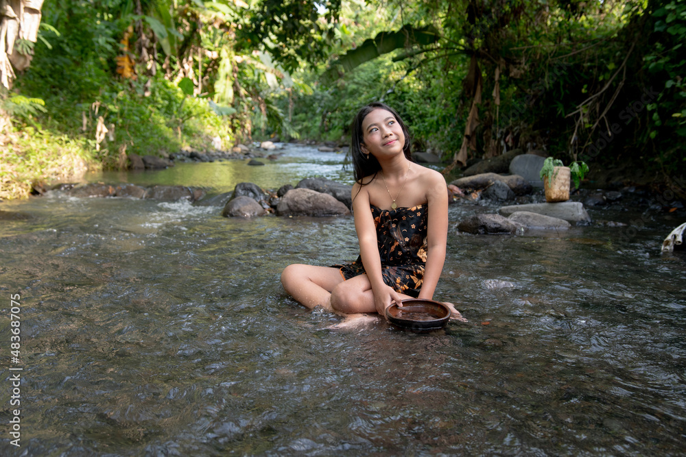 Fototapeta premium Beautiful young Asian girl rests and bathes in the river