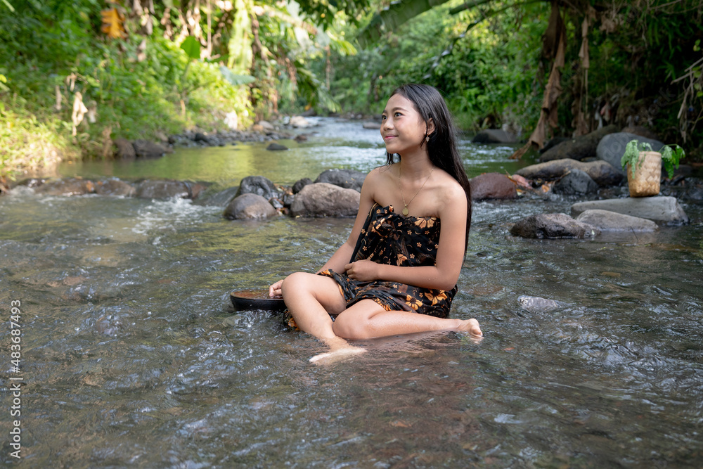 Fototapeta premium Beautiful young Asian girl rests and bathes in the river