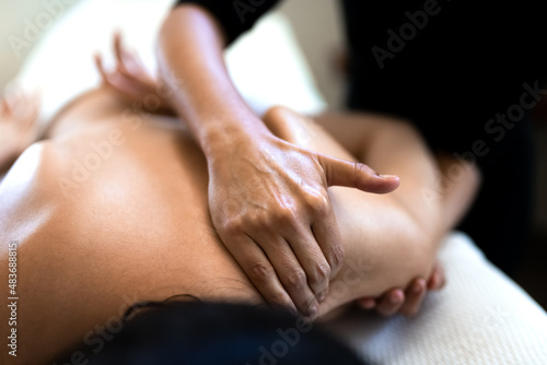 Close up of woman hands giving massage to upper back and shoulder blade.