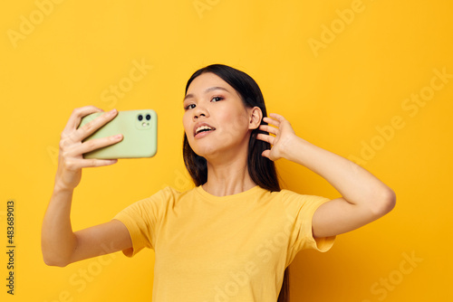 woman with Asian appearance in a yellow t-shirt looking at the phone posing Monochrome shot