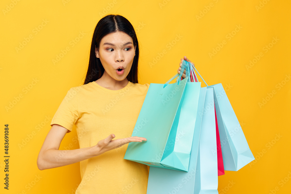 woman in a yellow T-shirt with multicolored shopping bags isolated background unaltered woman in a yellow T-shirt with multicolored shopping bags isolated background unaltered