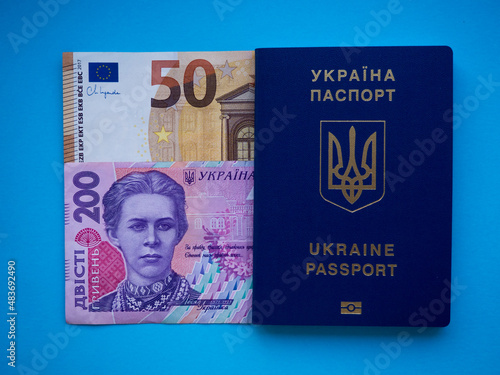 A set of European Union and Ukraine money with a face value of 50 euros and 200 hryvnia on blue. Background of the fifty euros, two hundred hryvnia banknotes and Ukraine passport with copy space. 