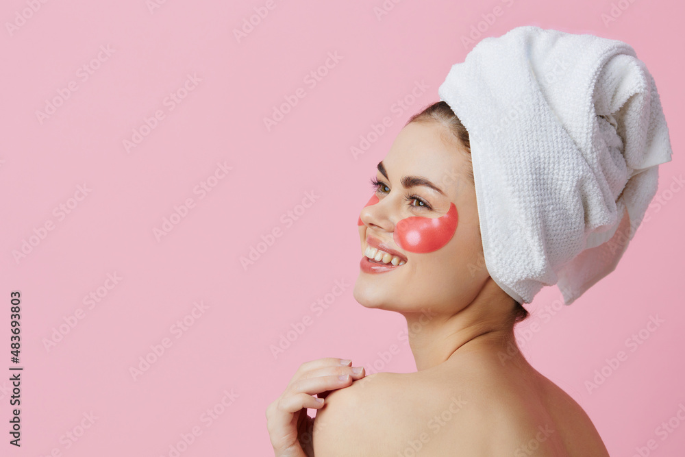 beautiful woman pink patches on the face with a towel on the head pink background beautiful woman pink patches on the face with a towel on the head pink background