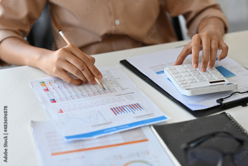 Fototapeta premium Close up with female accountant using calculator to calculate the numbers, finance accounting concept.